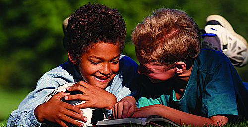 Two kids reading a book together