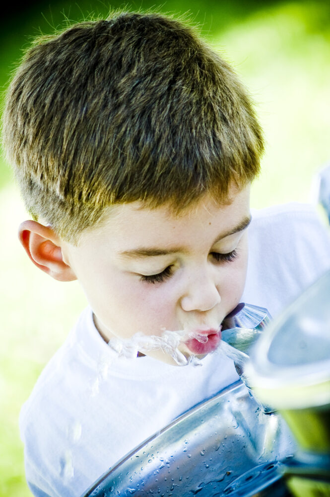 little boy drinking from fountain
