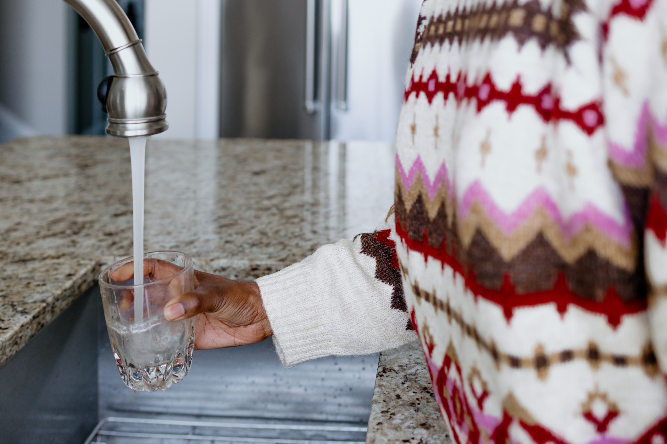 Woman filling a cup of tap water in sink