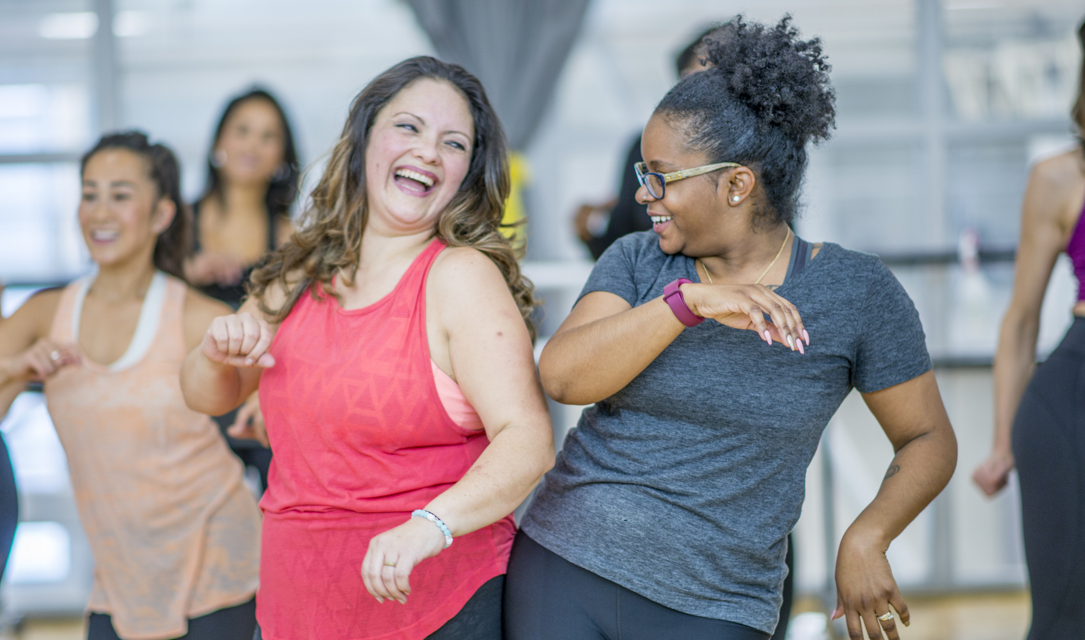 Two women in a zumba bumping hips and sharing a laugh.